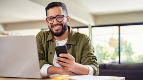 A man smiling while holding a smartphone