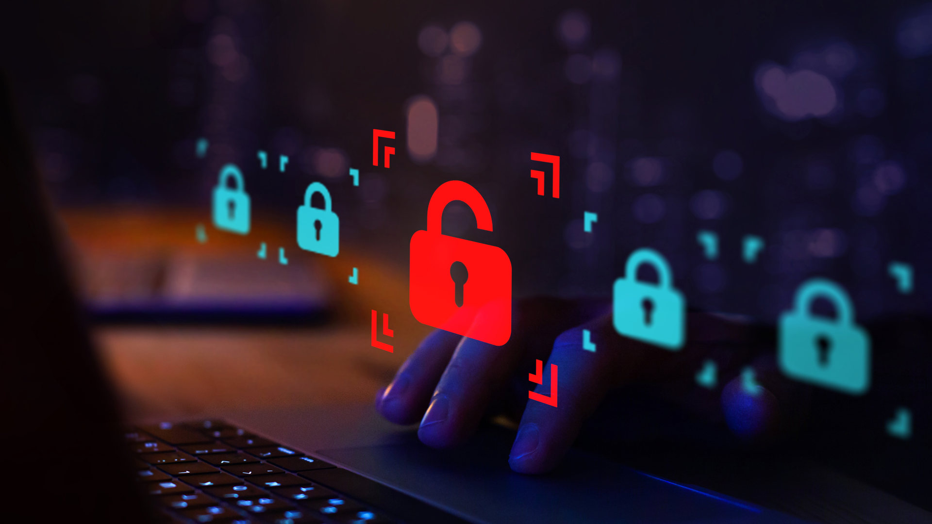A close-up of a hand using a laptop trackpad in a dark room